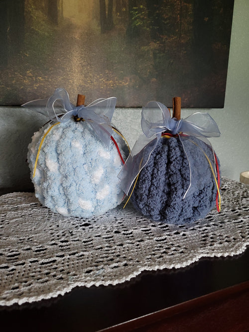 Hand‑knit blue chenille pumpkin pair with cinnamon‑stick stems and ribbon accents.