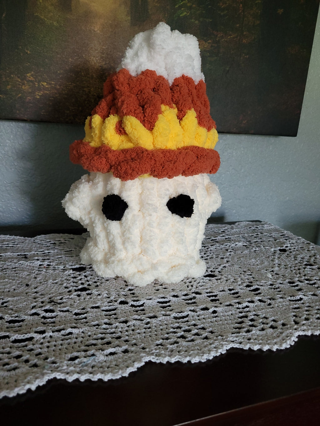 Hand‑knit chunky chenille ghost plush with a candy‑corn hat in white, yellow, and persimmon, featuring soft textured yarn and festive fall accents.
