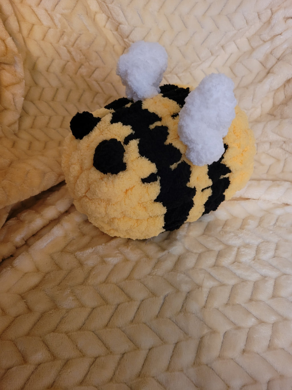 Angled view of handmade chunky‑chenille bumble bee plush showing wings and stripes.

Side view