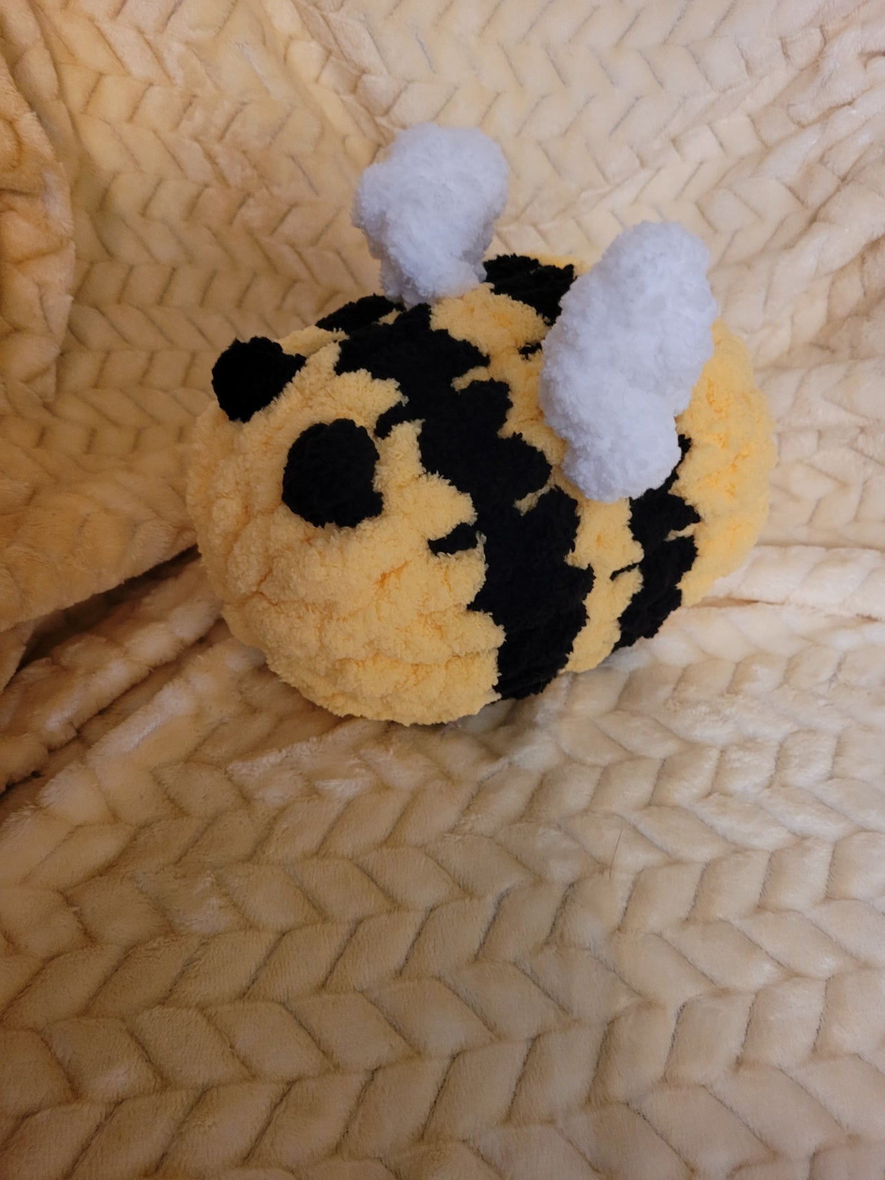 Angled view of handmade chunky‑chenille bumble bee plush showing wings and stripes.

Side view