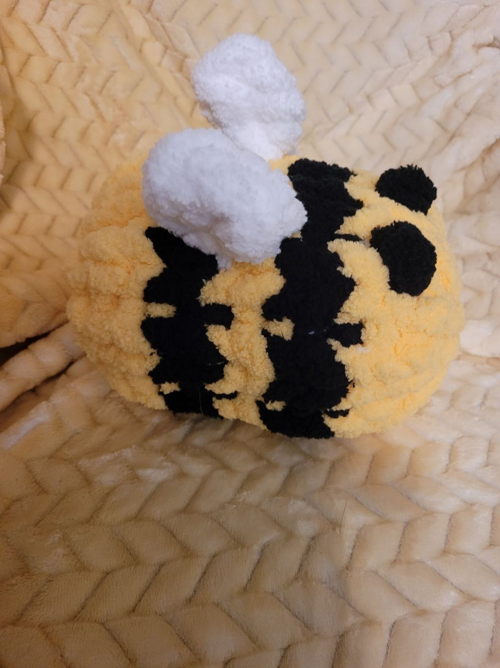 Angled view of handmade chunky‑chenille bumble bee plush showing wings and stripes.
