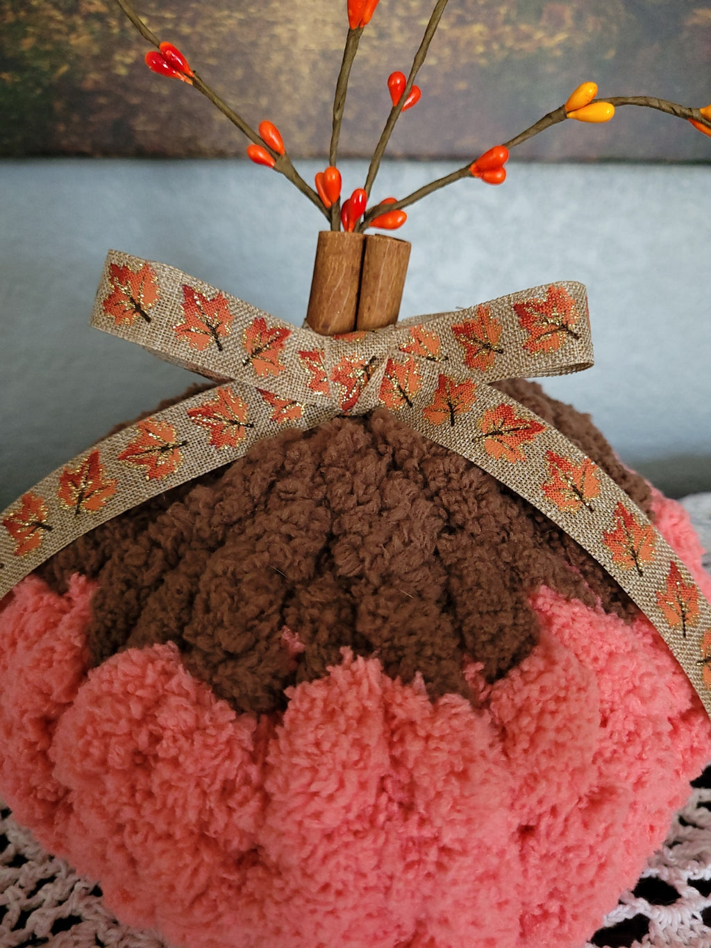 Close‑up of cinnamon‑stick stem, fall ribbon, and berry sprigs on handmade chenille pumpkin.