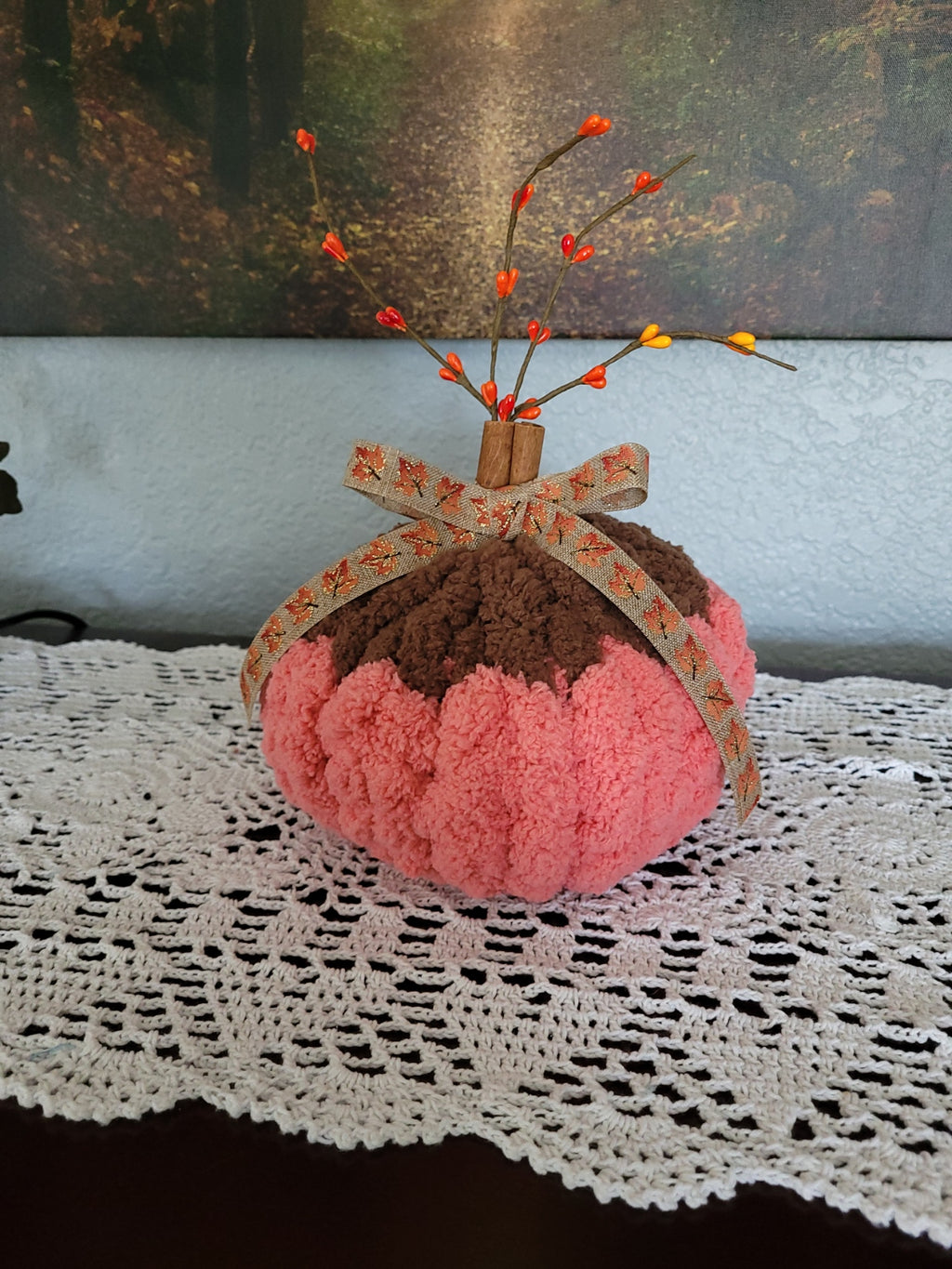 Angled view of handmade chenille pumpkin with orange base, brown top, ribbon bow, and berry accents.