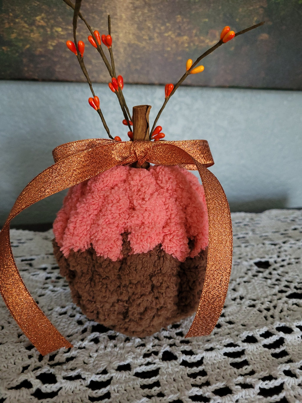 Close-up of cinnamon‑stick stem, ribbon, and berry sprigs on small handmade chenille pumpkin.