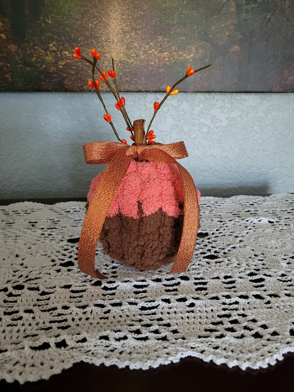Small handmade brown and orange chenille pumpkin with cinnamon‑stick stem and fall ribbon.
