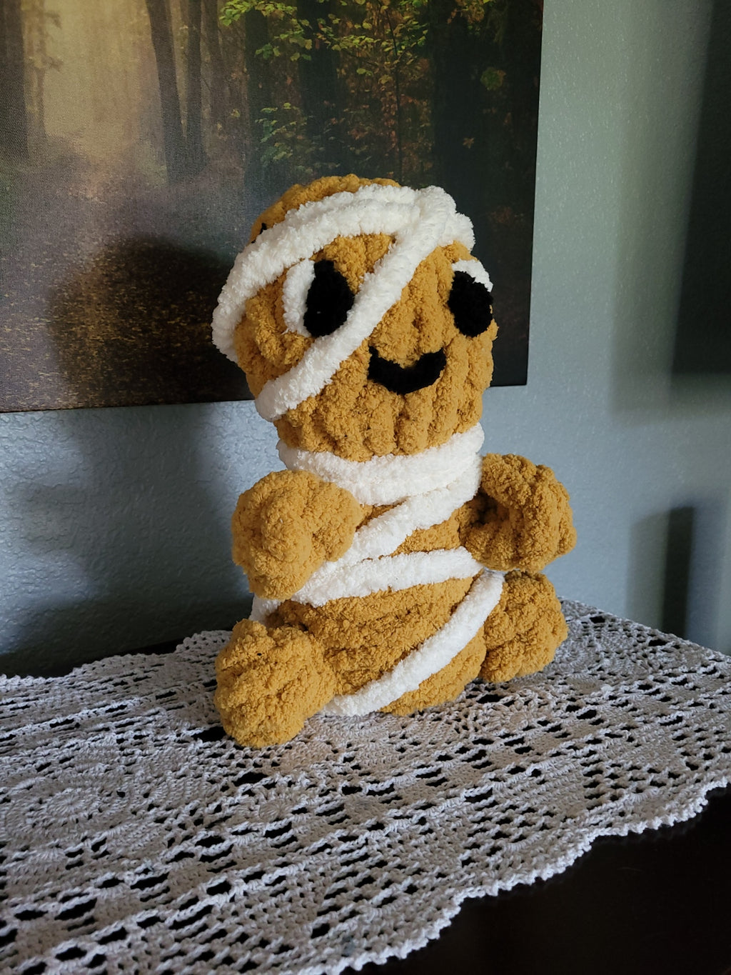 Side angle view of Tatterby, a cozy hand knit mummy plush in warm golden-brown and white chunky chenille yarn by CozyByBeverly