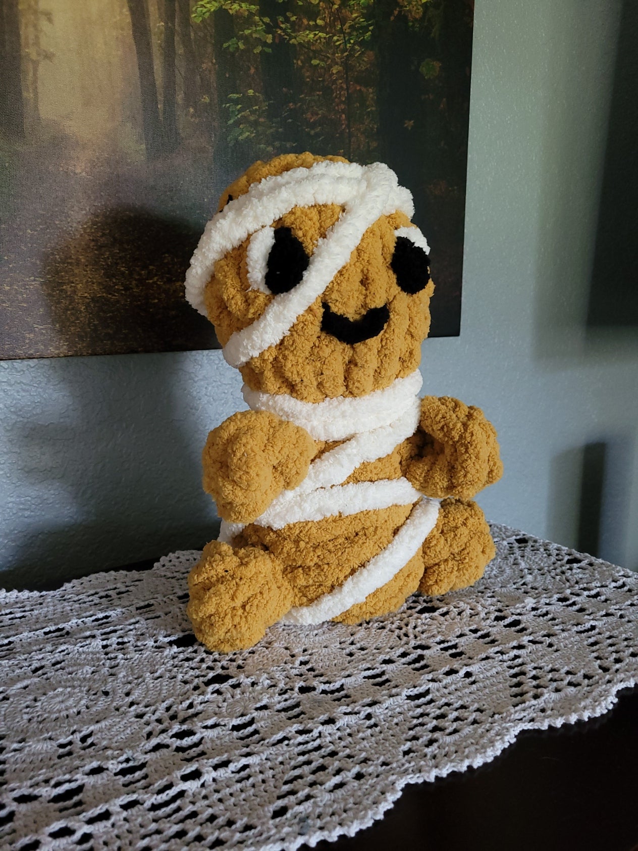 Side angle view of Tatterby, a cozy hand knit mummy plush in warm golden-brown and white chunky chenille yarn by CozyByBeverly