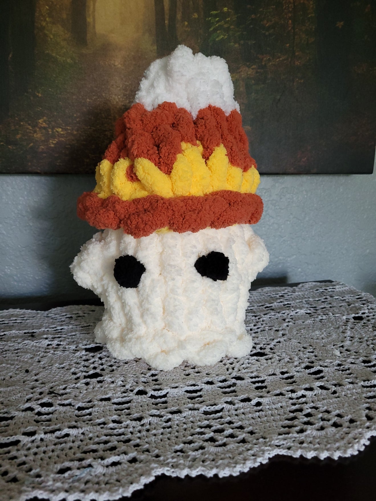 Hand‑knit chunky chenille ghost plush with a candy‑corn hat in white, yellow, and persimmon, featuring soft textured yarn and festive fall accents.